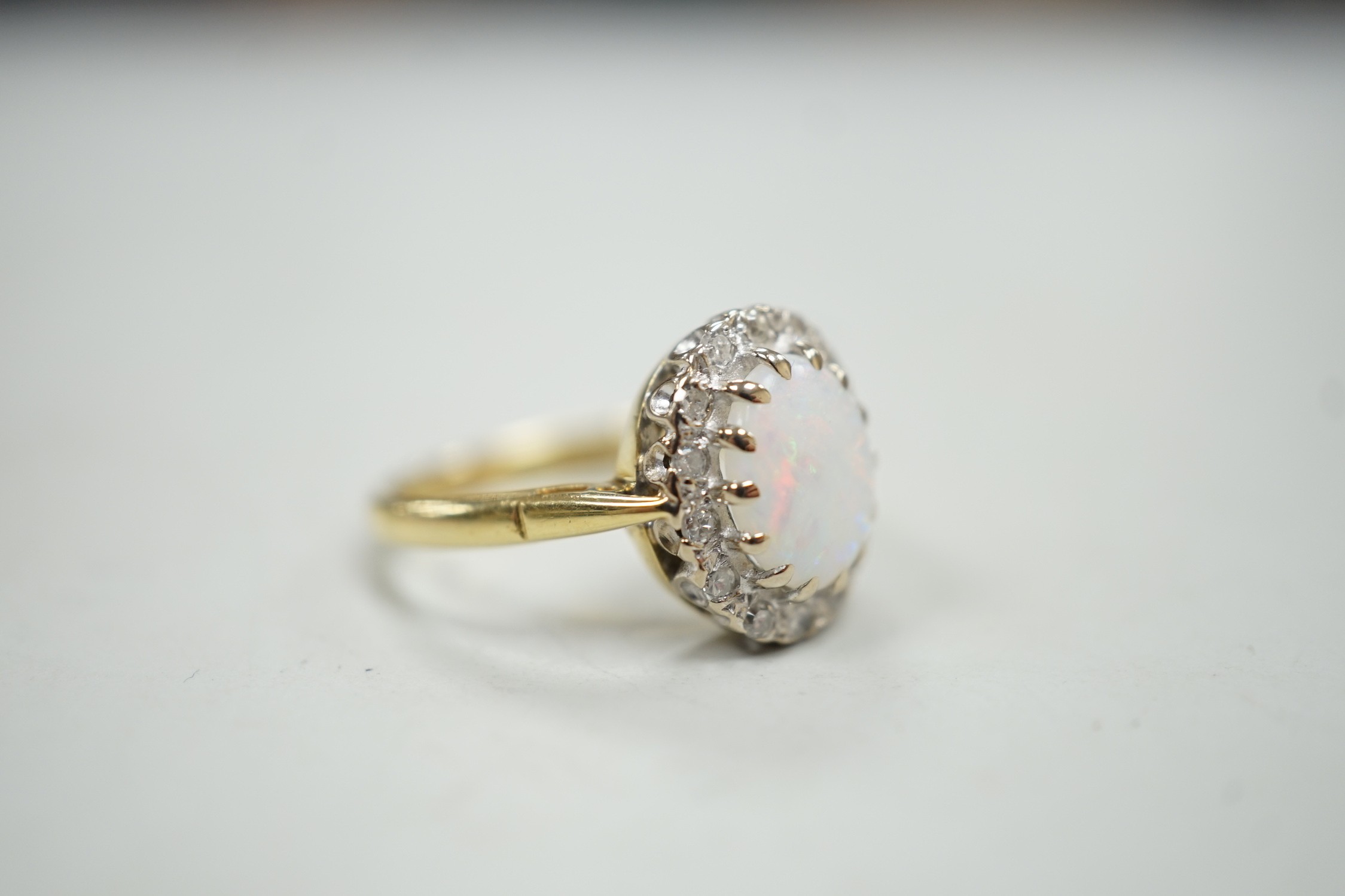 A modern 18ct white gold white opal and diamond set oval cluster ring, size M, gross weight 4.3 grams.